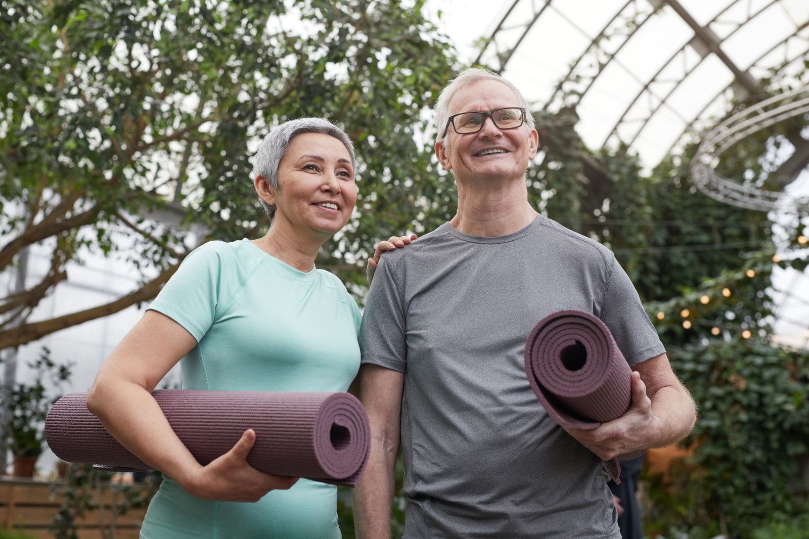 Smiling middle-aged couple holding yoga mats, ready for an active day